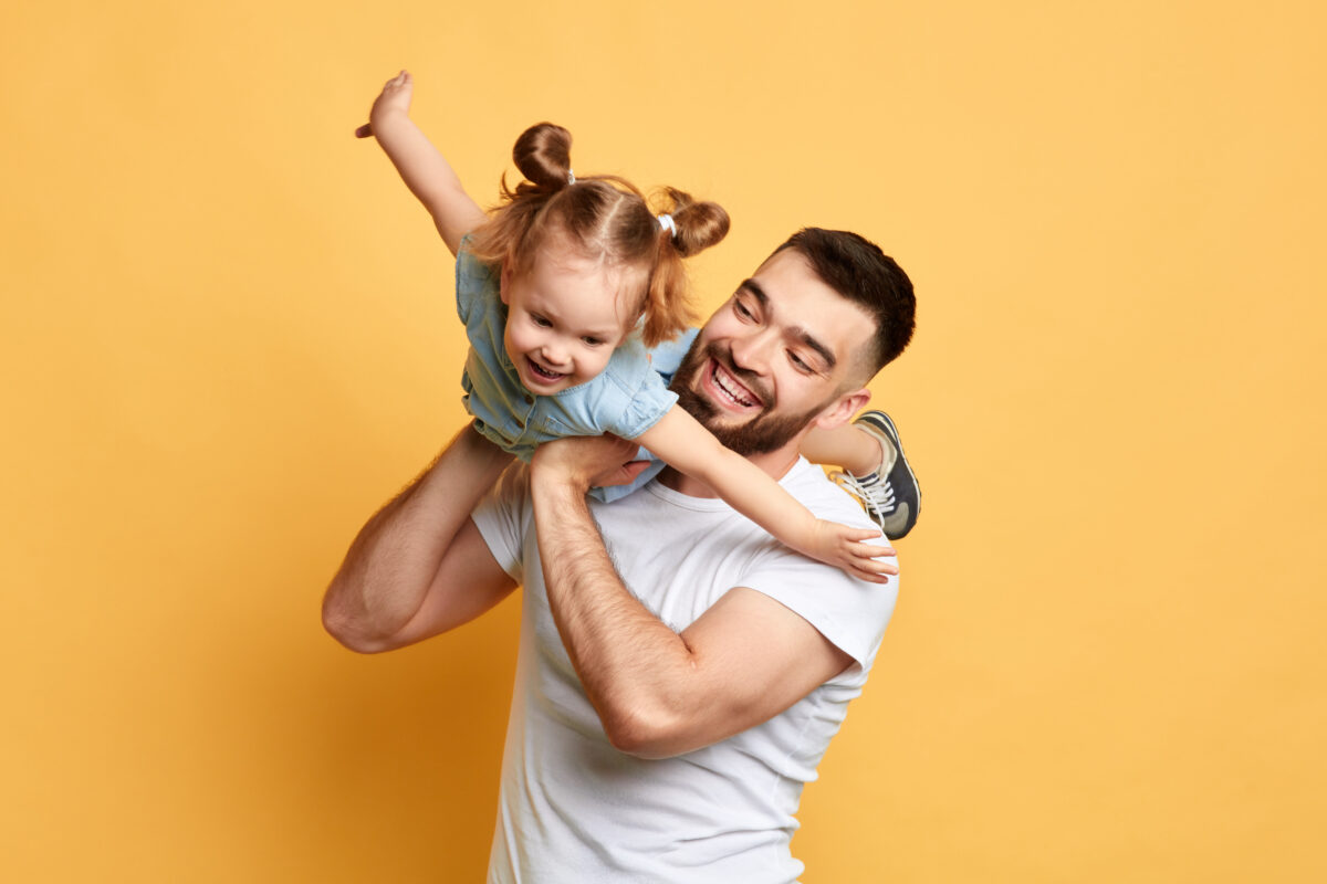 cheerful happy man teaching sweet lovely daughter to fly like a plane